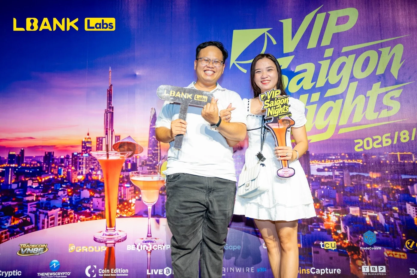 Attendees posing with LBank Labs props at the VIP Saigon Nights photo backdrop